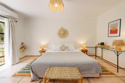 a white bedroom with a bed and a table at Le mas de l'Ourika, maison d'hôtes in Aït Zat