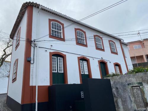 a white and red house with red windows at Apartamento Memória in Angra do Heroísmo