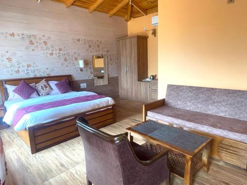 a bedroom with a bed and a table and a couch at Sangita Resorts in Nainital
