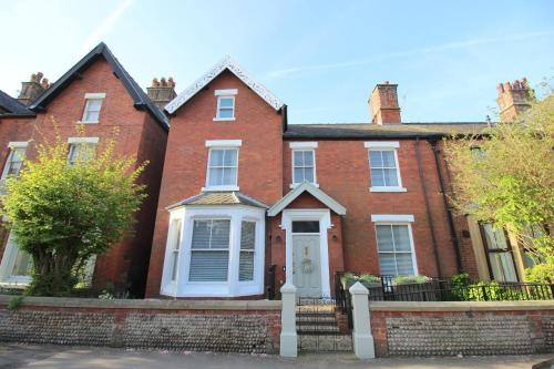 a red brick house with a white door at The Bungalow and Studio Apartments in Lytham St Annes