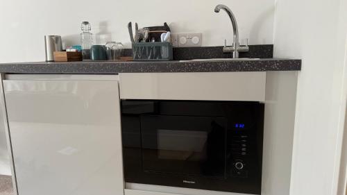 a kitchen counter with a microwave and a sink at Watermead House in Chard