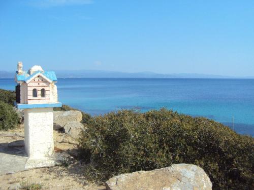 a small building on the side of a hill near the ocean at Ormos View Apartments in Ormos Panagias