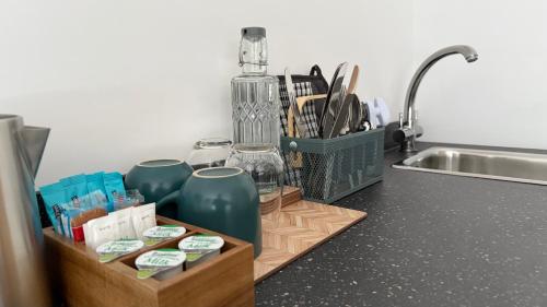 a kitchen counter with a sink and a tray with cups at Watermead House in Chard