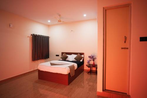 a bedroom with a bed and a door to a room at Hotel Pergola - Mysore in Chāmundi