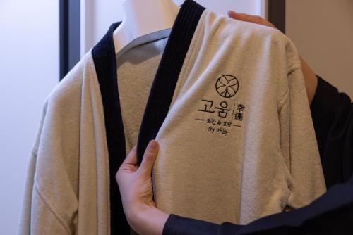 a person holding a sweater with a label on it at Koum Ryokan Hotel Gijang by Aank in Busan