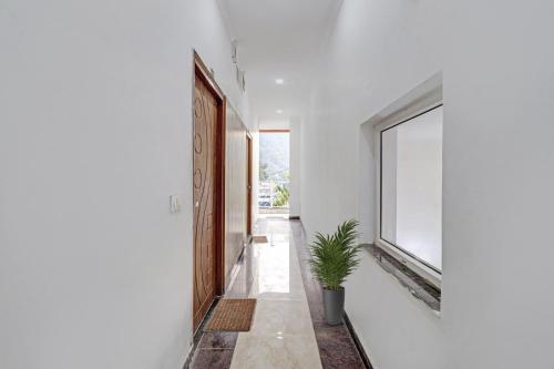 a hallway with a door and a potted plant at HOTEL O LAXMAN GRAND in Tapovan