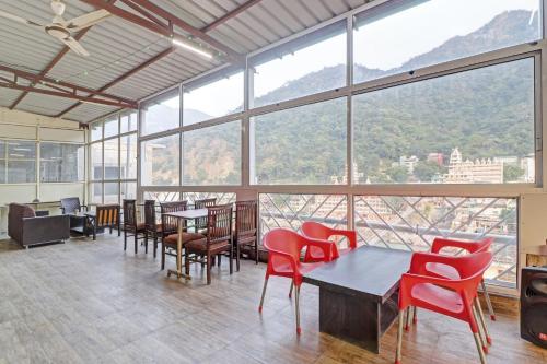 a room with red chairs and tables and windows at HOTEL O LAXMAN GRAND in Tapovan