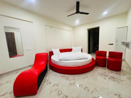 a bedroom with a bed and two red chairs at Hotel Wow Inn - Dhanori-Lohegaon Rd, Parande Nagar, Dhanori, Pune in Pune