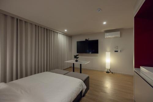 a bedroom with a bed and a tv on the wall at Koum Ryokan Hotel Gijang by Aank in Busan