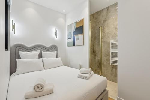 Un dormitorio con una cama blanca y una ducha. en Appartement Guersant Pereire, en París