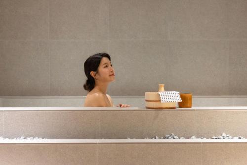a woman is sitting in a bath tub at Koum Ryokan Hotel Gijang by Aank in Busan