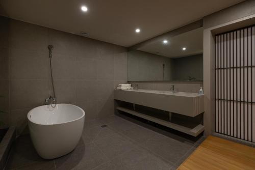 a bathroom with a tub and a large mirror at Koum Ryokan Hotel Gijang by Aank in Busan