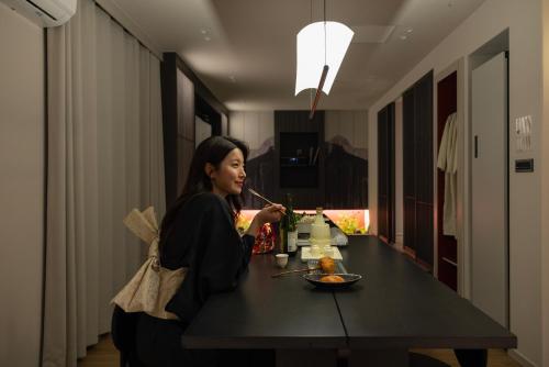 a woman sitting at a table eating food at Koum Ryokan Hotel Gijang by Aank in Busan