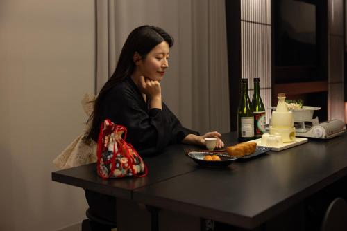 a woman sitting at a table with a plate of food at Koum Ryokan Hotel Gijang by Aank in Busan