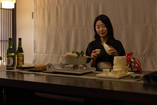 a woman sitting at a table looking at her cell phone at Koum Ryokan Hotel Gijang by Aank in Busan