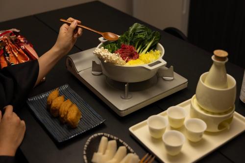 a table with a bowl of food and a person holding chopsticks at Koum Ryokan Hotel Gijang by Aank in Busan
