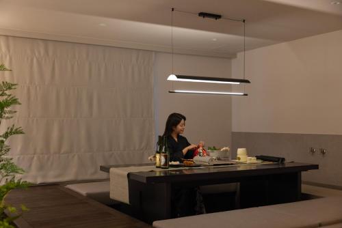 a woman sitting at a table in a room at Koum Ryokan Hotel Gijang by Aank in Busan