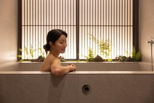 a young girl sitting in a bath tub at Koum Ryokan Hotel Gijang by Aank in Busan