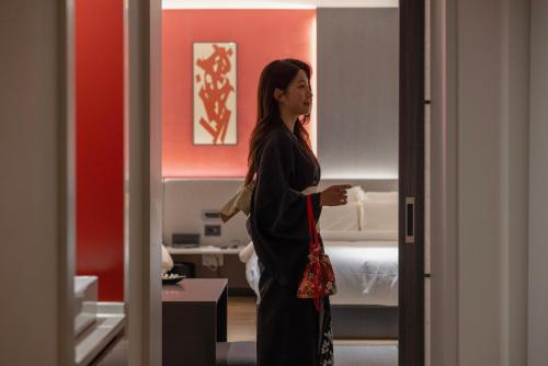 a woman standing in a room with a bed at Koum Ryokan Hotel Gijang by Aank in Busan