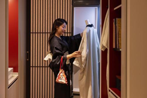 a woman is looking at a dress in a closet at Koum Ryokan Hotel Gijang by Aank in Busan