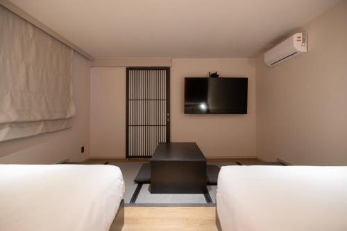 a room with two beds and a flat screen tv at Koum Ryokan Hotel Gijang by Aank in Busan