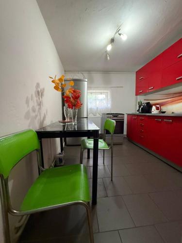 a kitchen with a table with green chairs and red cabinets at Domeček Drahuška in Janov
