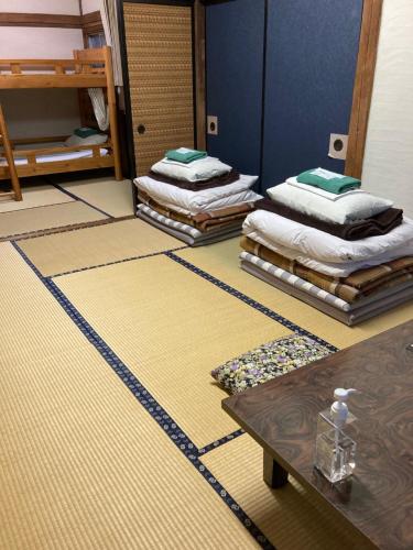 a room with three mattresses on the floor and a table at Wafu Guesthouse Kashiwaya in Fujikawaguchiko