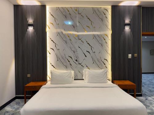 a bedroom with a large bed with white sheets at Al Massa Plus Hotel in Al Ain