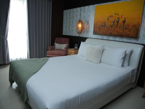 a bedroom with a large white bed and a chair at iVilla in Jimbaran