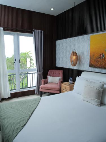 a bedroom with a white bed and a pink chair at iVilla in Jimbaran