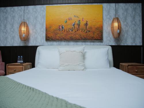 a bedroom with a white bed with a painting above it at iVilla in Jimbaran