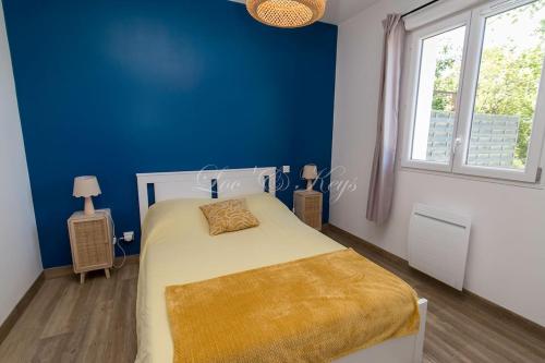- une chambre bleue avec un lit et une couverture jaune dans l'établissement Appartement de vacances avec terrasse et petit jardin, à Parentis-en-Born