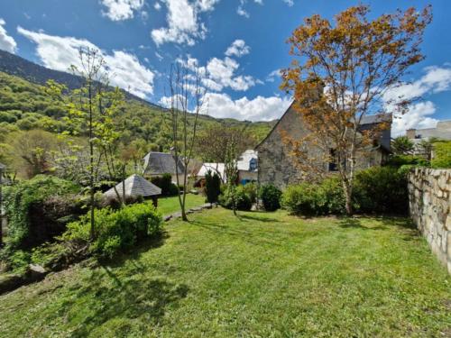 a house with a yard with a stone wall at Maison La Flambée in Bordères-Louron