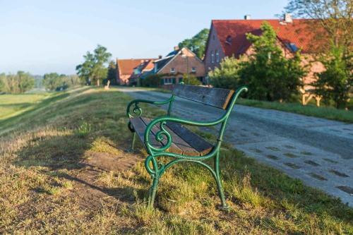 a green park bench sitting on the side of a road at Reetdachhaus mit Elbblick in Lenzerwische