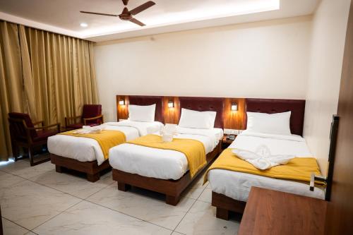 a hotel room with two beds with yellow sheets at Hotel The Pearl Shine in Gokarna