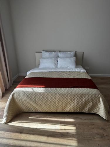 a bed with a red and white blanket on the floor at Апартаменты Aktau Rivera in Aktau