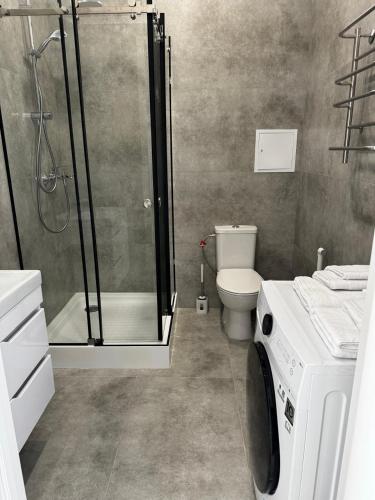 a bathroom with a shower and a washing machine at Апартаменты Aktau Rivera in Aktau