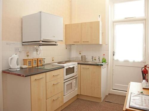 a kitchen with white appliances and wooden cabinets at The Meltham Guesthouse Scarborough in Scarborough
