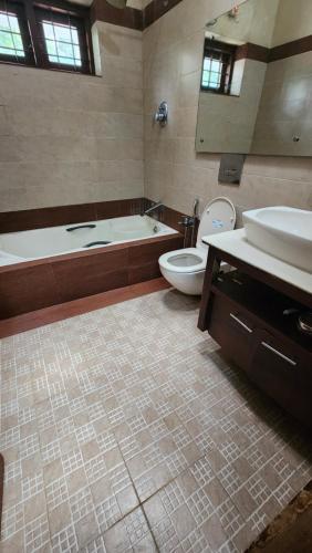 a bathroom with a tub and a toilet and a sink at The Palmyra Estate - by Cocoon, A Luxury Party Villa near Varkala in Paravūr