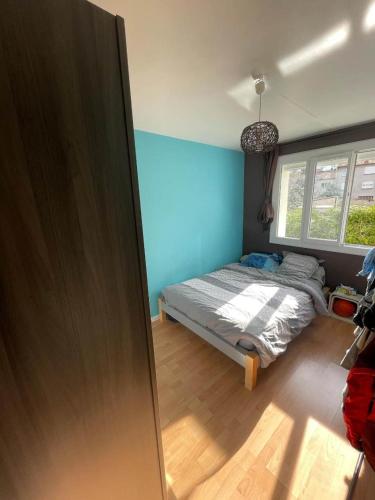 Un dormitorio con una cama y una pared azul. en Joli T2 proche de la gare, en Clermont-Ferrand