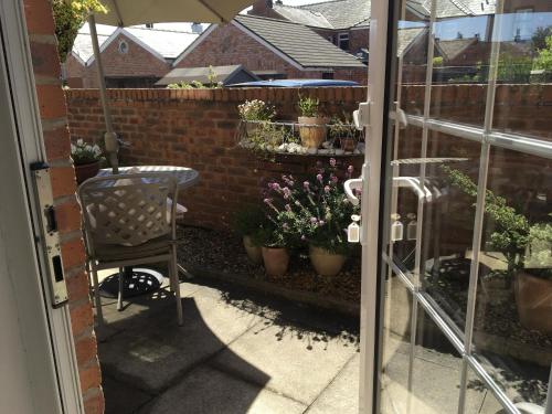 a patio with a chair and potted plants on a fence at The Bungalow and Studio Apartments in Lytham St Annes