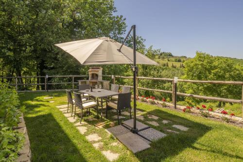 a table and chairs under an umbrella in a yard at Villetta Cafaggio, Ac, Wifi, Panzano In Chianti in Castellina in Chianti
