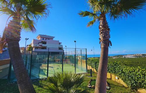 a tennis court with palm trees in front of a building at Costa Brisas in Almayate Alto