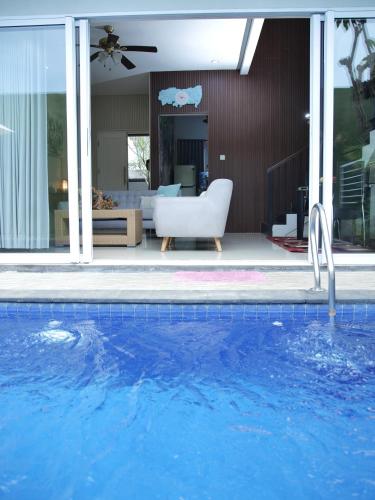 a swimming pool with a white chair next to a bedroom at iVilla in Jimbaran
