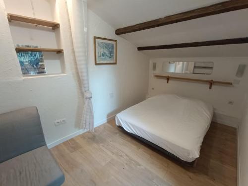 - une petite chambre avec un lit blanc et du parquet dans l'établissement Domaine des anges, à Tourves