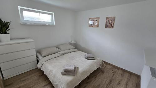 a white bedroom with a bed and a window at Xela Apartment in Sklenárovo