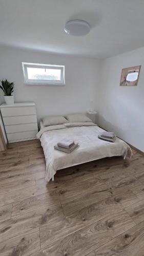 a white bedroom with a bed and wooden floors at Xela Apartment in Sklenárovo