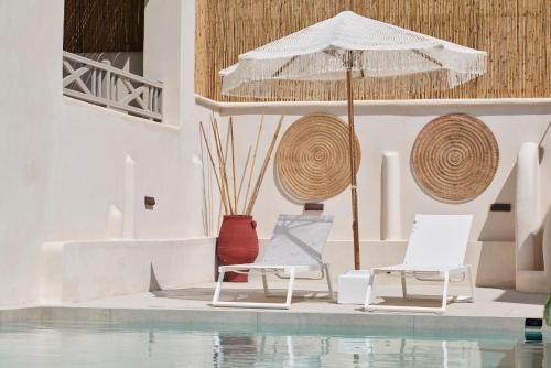two chairs and an umbrella next to a pool at Salt Suites Paros in Naousa