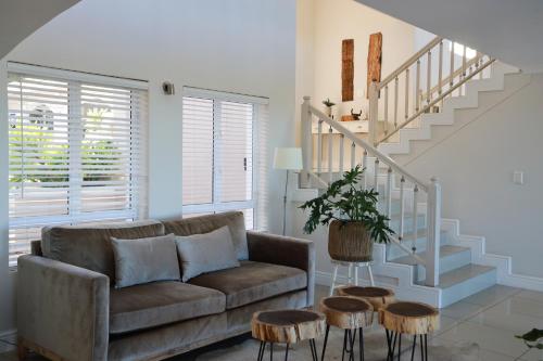 a living room with a couch and a staircase at Pezula 's Paradise in the Sun - No Loadshedding in Knysna