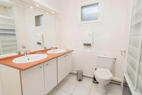 La salle de bains blanche est pourvue de 2 lavabos et de toilettes. dans l'établissement 4-person duplex house, 2-star rating, à Biscarrosse